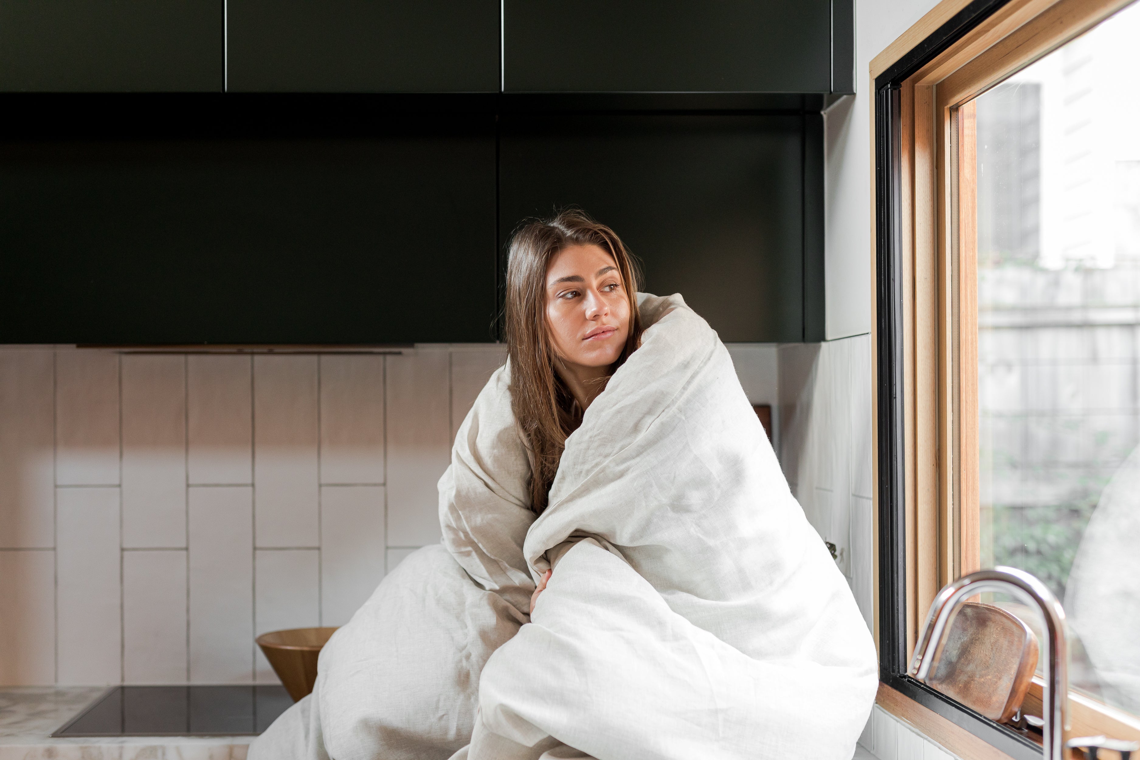Woman looking out window with duvet