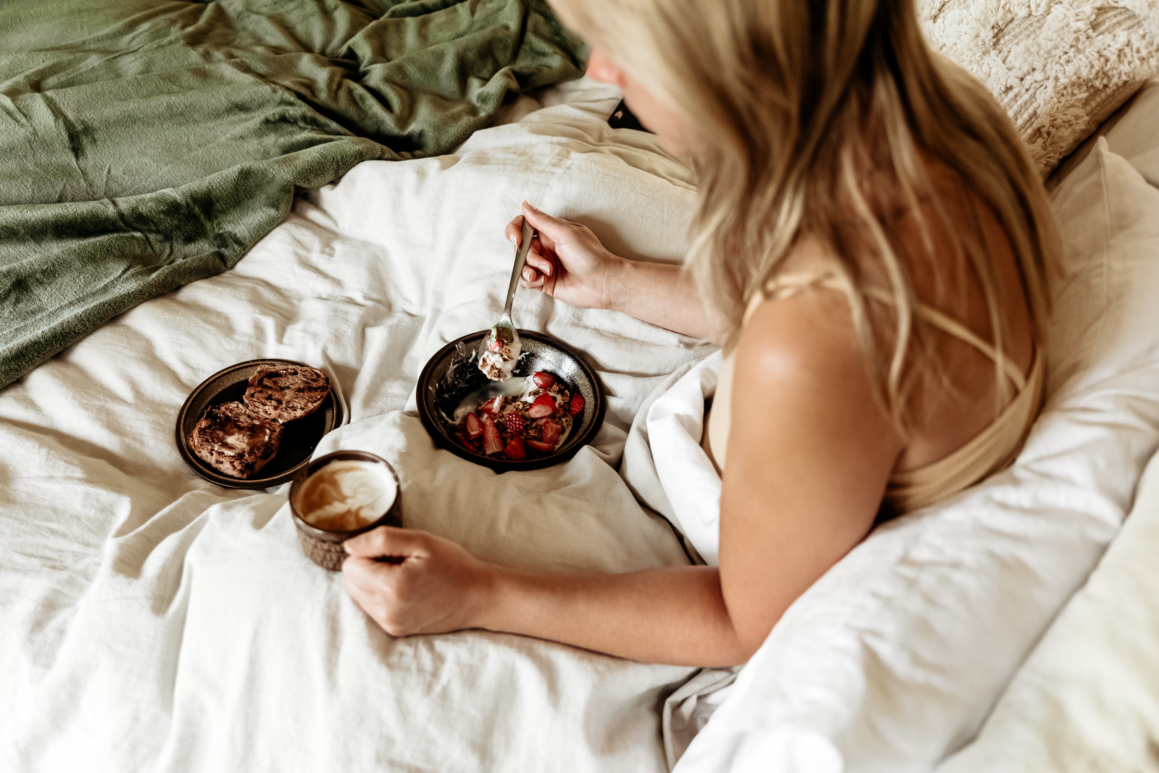 Woman eating breakfast in bed on Eva Mattress