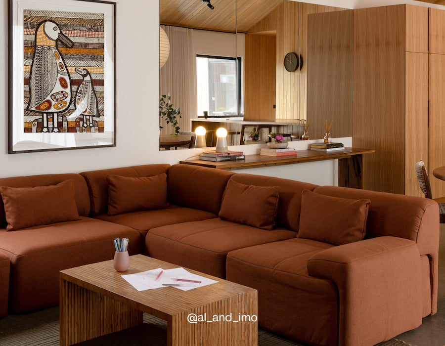 Brown sectional sofa in a living room with a coffee table and decorative items.