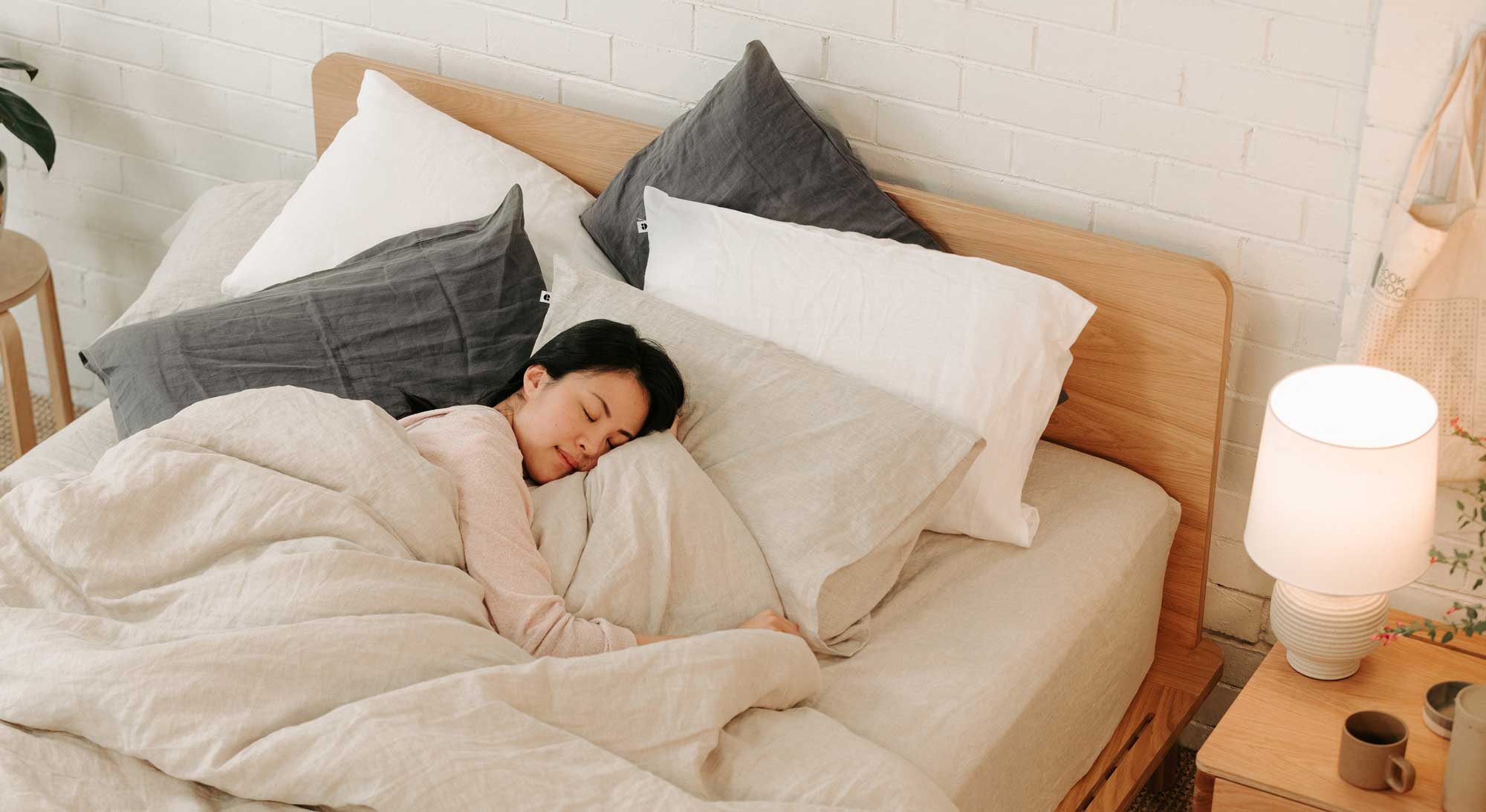 Woman looking cosy covered in hemp linen sheets and pillows